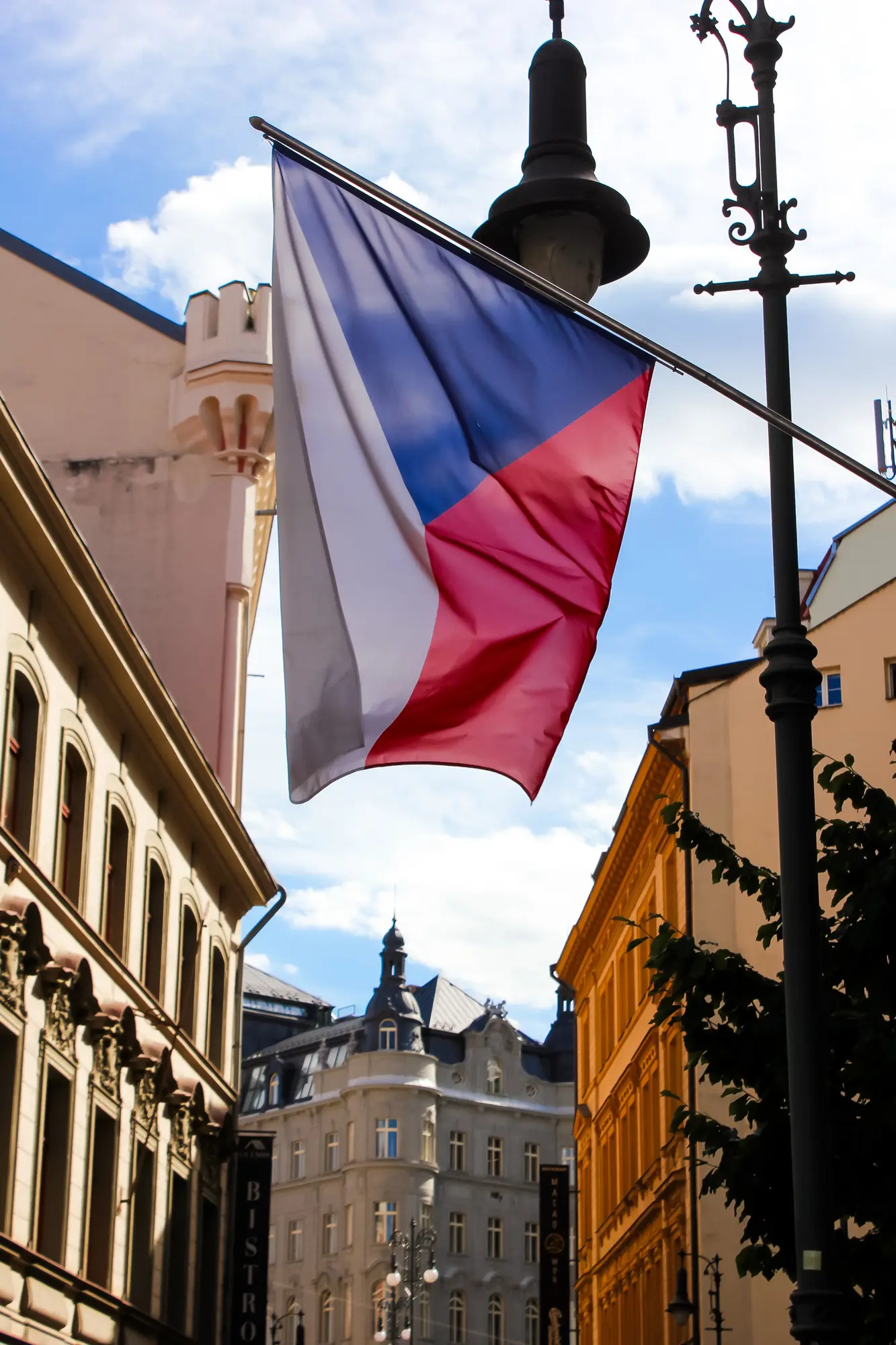 Česká vlajka mezi historickými domy v Praze
